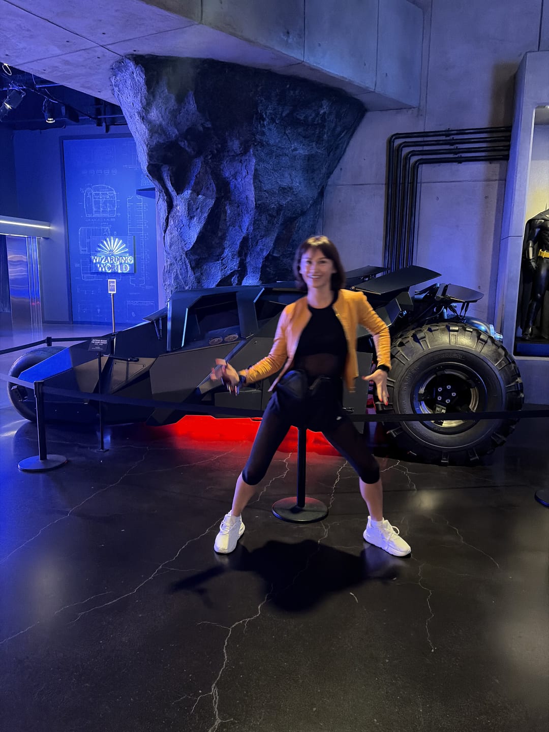 Masha posing beside a futuristic black vehicle under blue lighting.